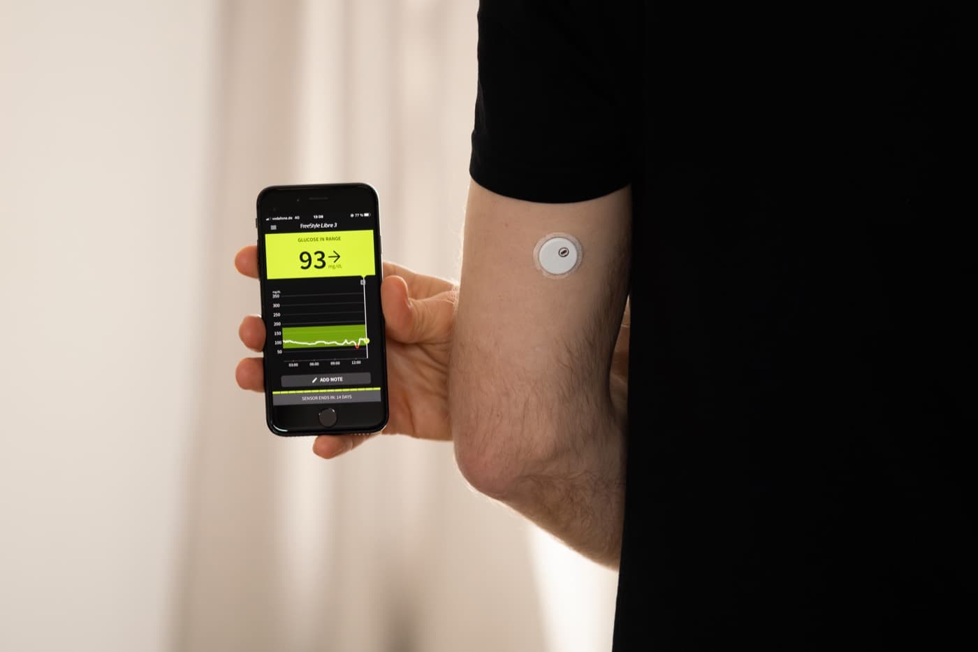 A man checking his glucose reading on his phone, CGM sensor on his arm