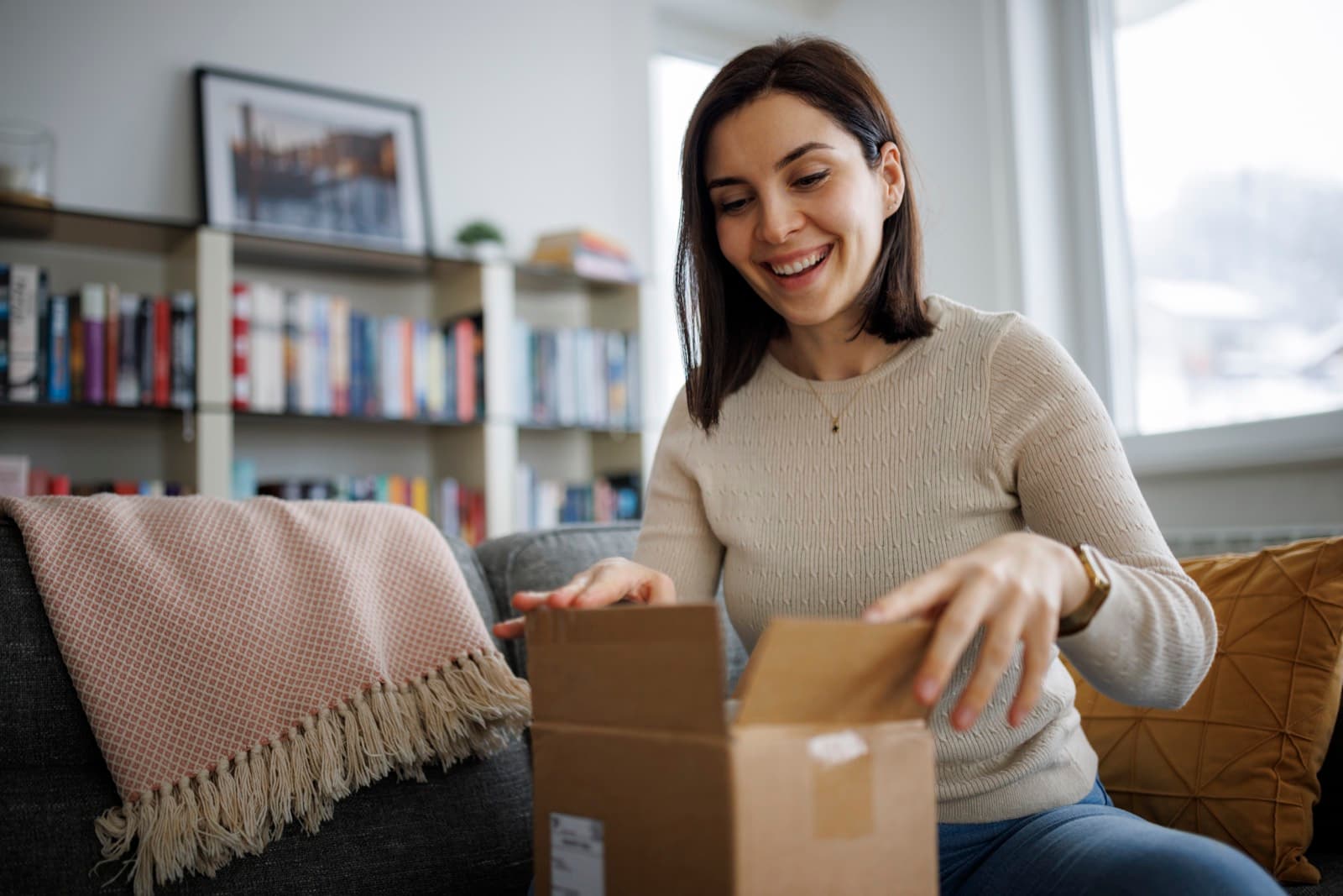 A woman smiling as she opens her delivery box at home